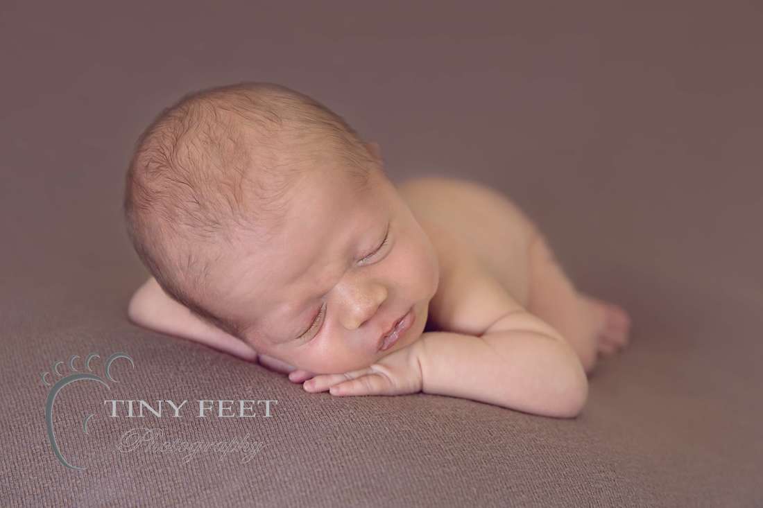 Tiny Feet Photography Newborn baby boy  on chin on hands on brown backdrop