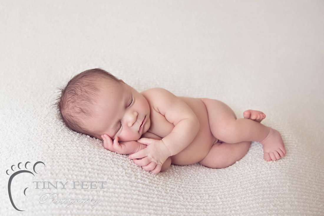Tiny Feet Photography Newborn boy side pose on cream blanket