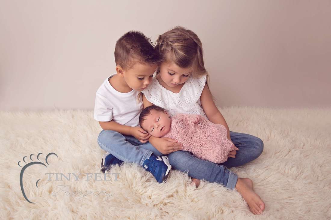 Tiny Feet Photography newborn baby girl wrapped in pink posed with siblings
