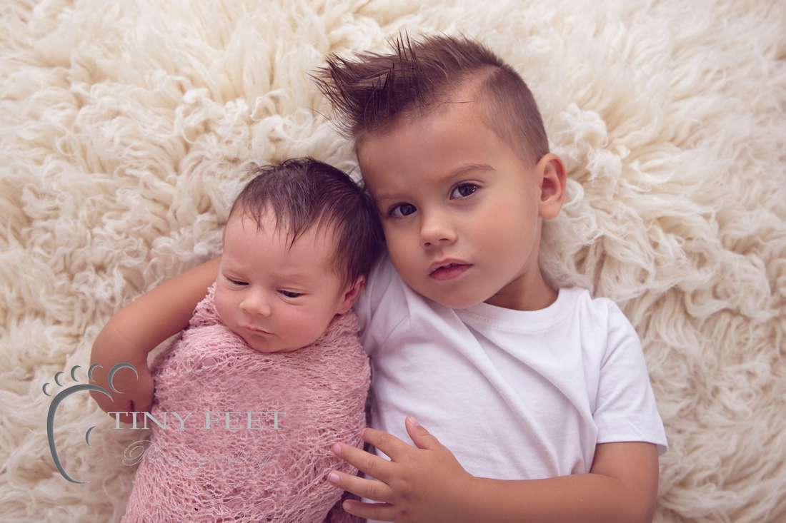 Tiny Feet Photography newborn baby girl wrapped in pink posed with big brother