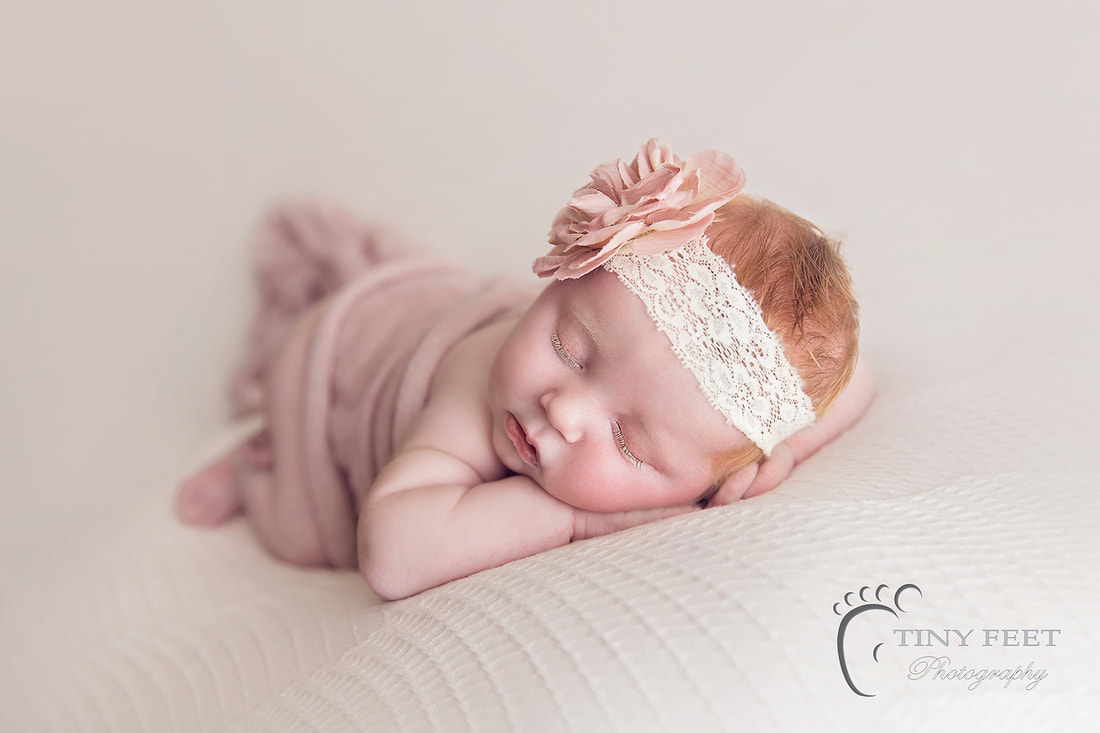 Tiny Feet Photography baby girl chin on hand pose on white newborn posing blanket