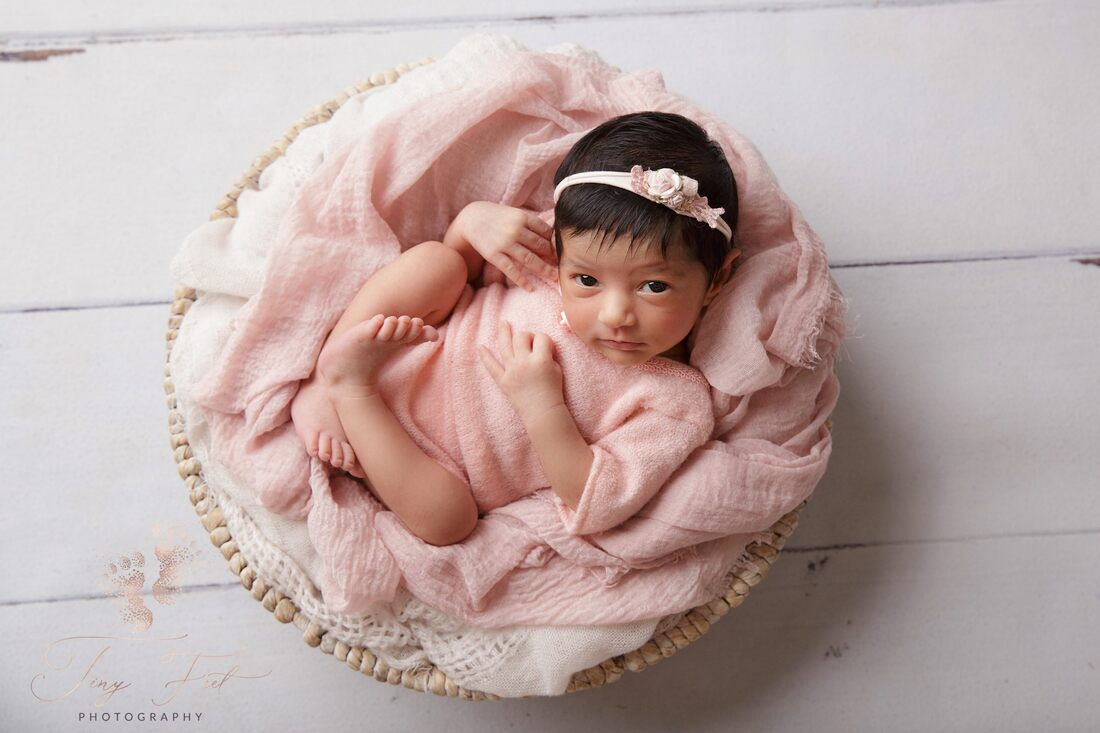 Tiny Feet Photography image of a sweet baby girl in pink outfit photographed with a white bowl and pick and white fabrics 