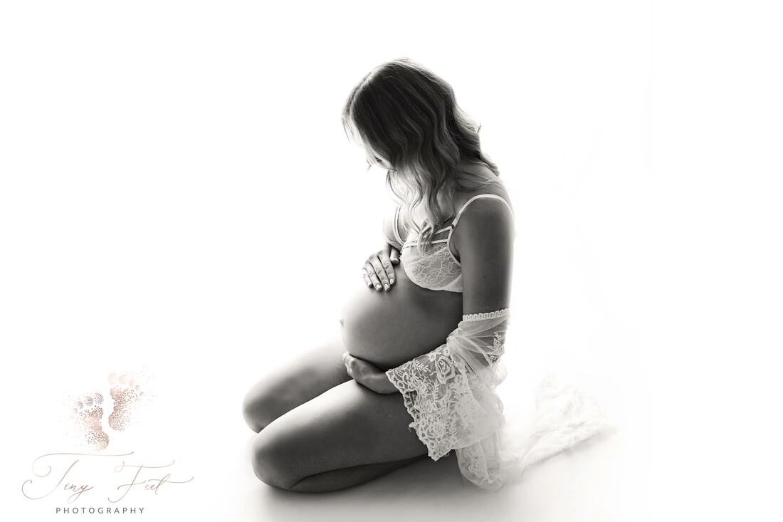 Tiny Feet Photography Black and white back lit studio maternity image of mum to be on her knees looking at her belly