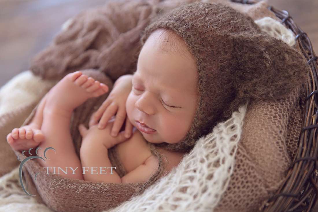 Tiny Feet Photography Newborn baby boy posed in brown wraps backlit in bowl