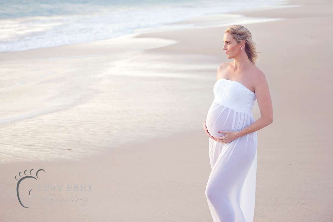 Sunset maternity photos with mum in white dress looking at ocean