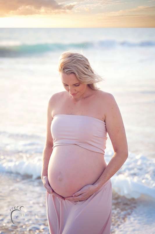 Maternity beach photography, mum looking down in pink gown