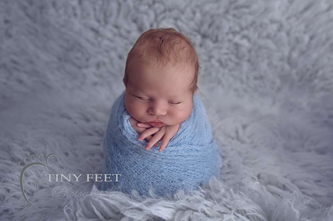 Tiny Feet Photography, newborn baby wrapped in blue on Flokati in the potato sack pose