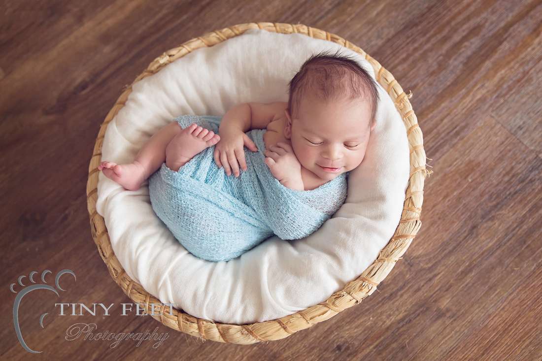 Tiny Feet Photography Newborn boy wrapped in blue and posed in basket