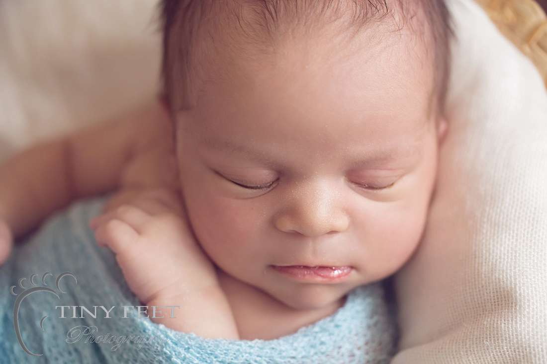 Tiny Feet Photography Newborn boy wrapped in blue close up shot of face
