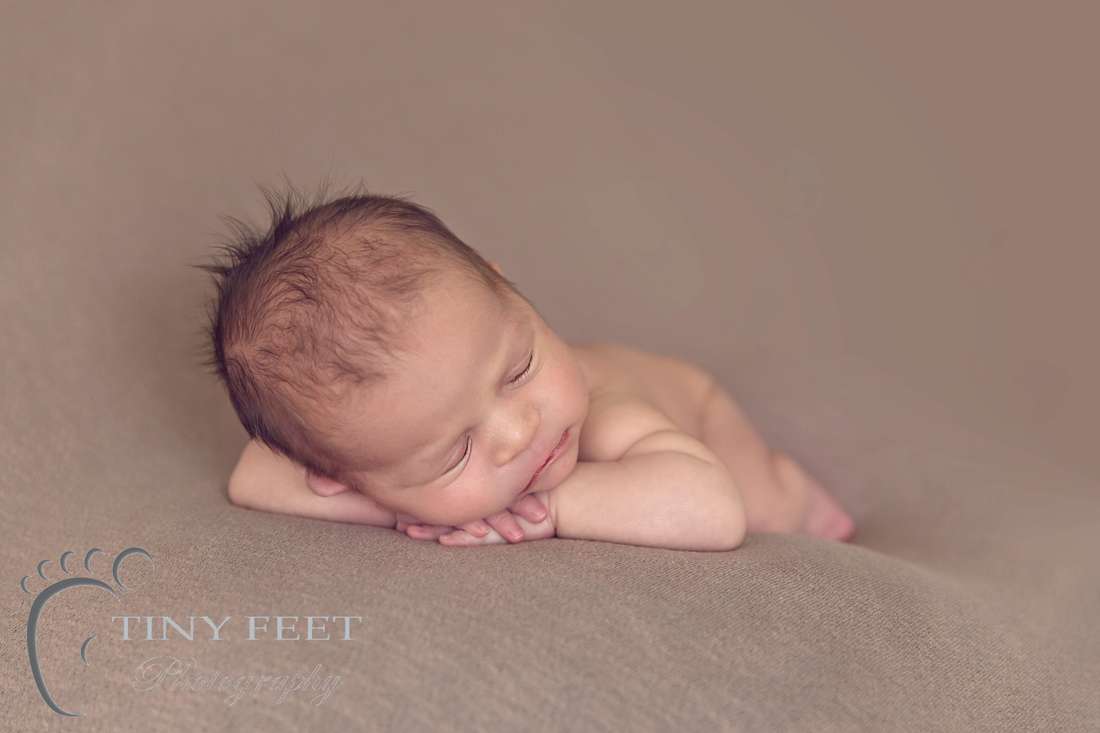 Tiny Feet Photography Newborn boy on chin on hand pose on brown blanket