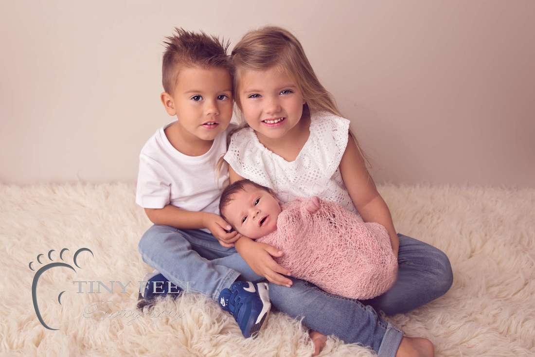 Tiny Feet Photography newborn baby girl wrapped in pink posed with siblings
