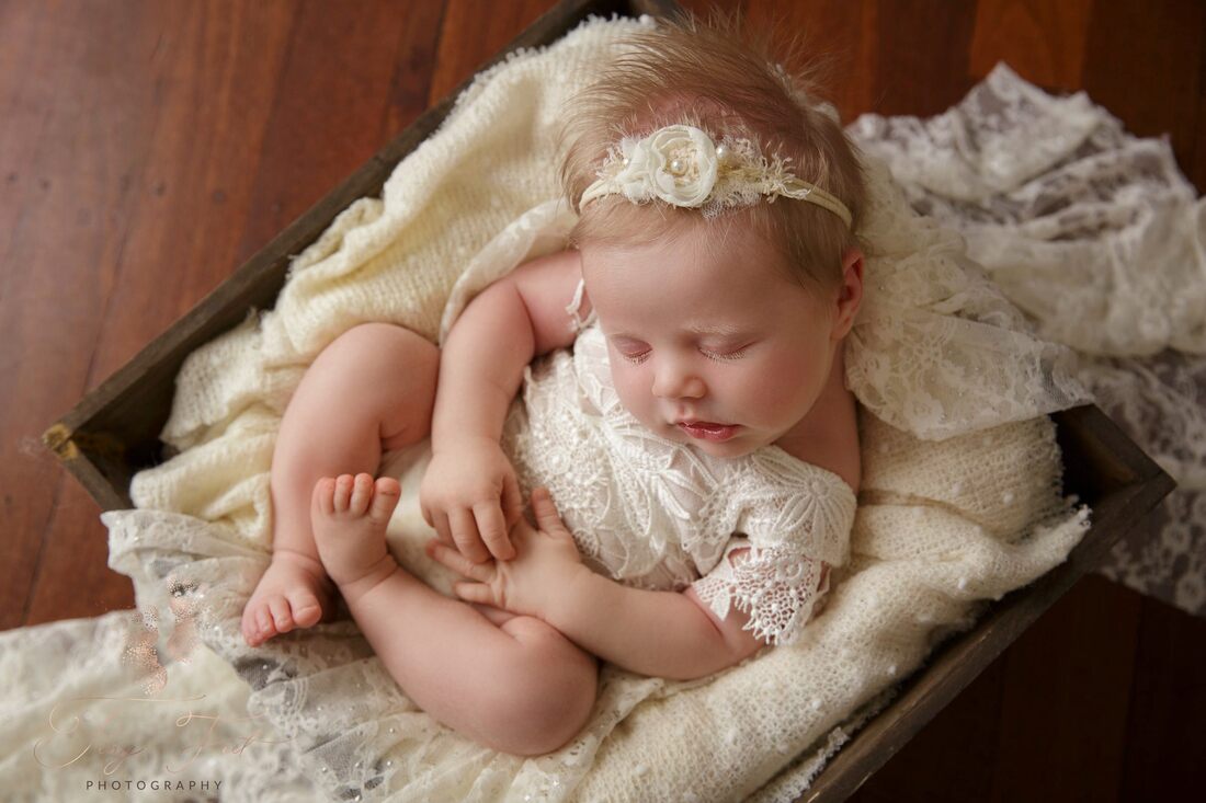Tiny Feet Photography shot of baby girl and lace in a wooden box with dark wood flooring  