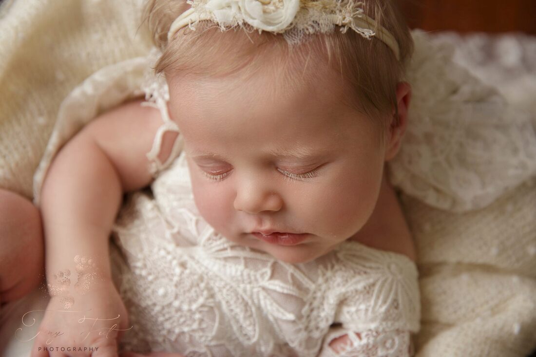 Tiny Feet Photography close up shot of baby girls face and features and lace in a wooden box with dark wood flooring  