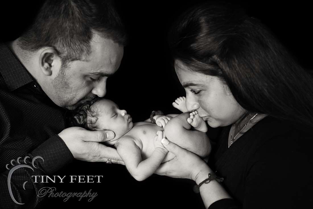 Tiny Feet Photography newborn baby posed in mum and dads hands in black and white