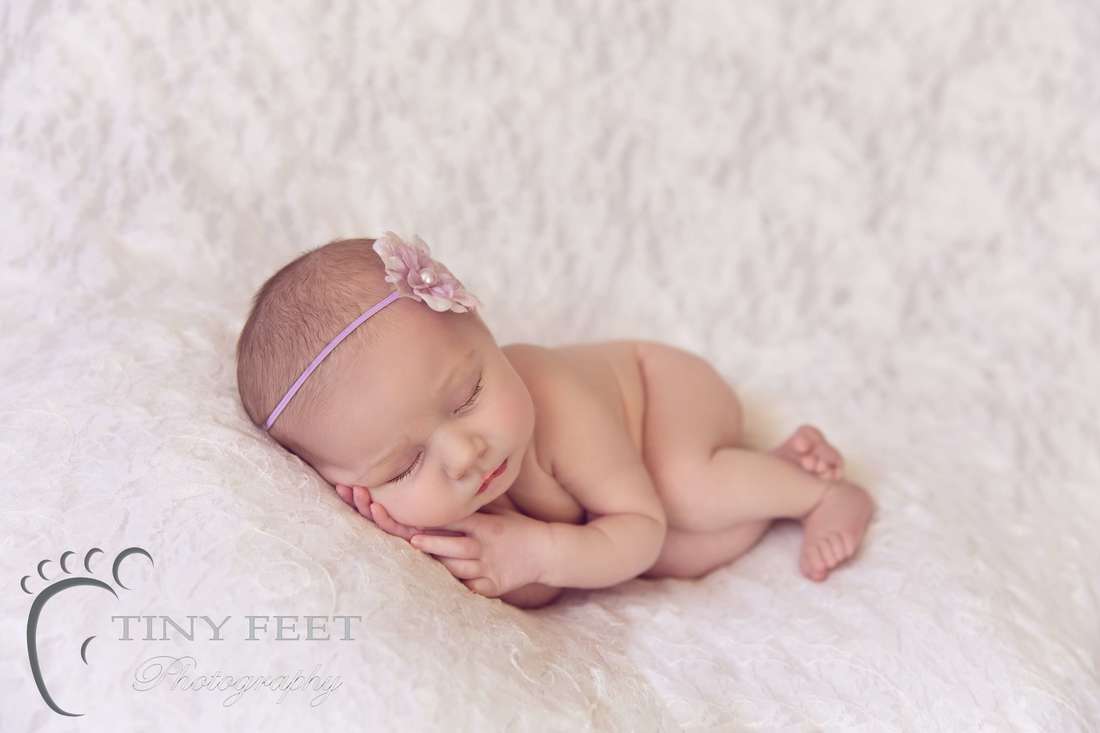 Tiny Feet Photography Newborn baby girl in side laying pose laying on white lace blanket
