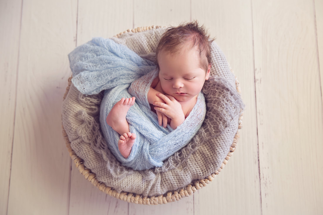 Tiny Feet Photography Newborn baby boy in blue and grey in white basket and white floor boards