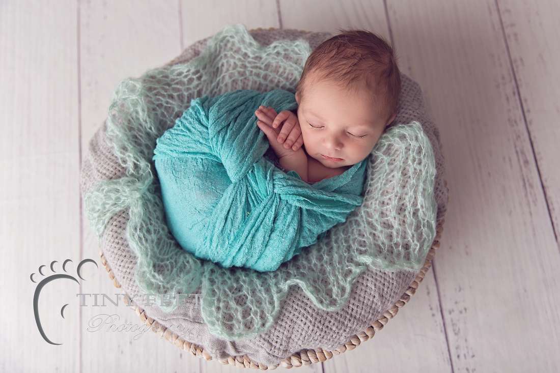 Tiny Feet Photography baby boy wrapped in green wrap in a grey basket