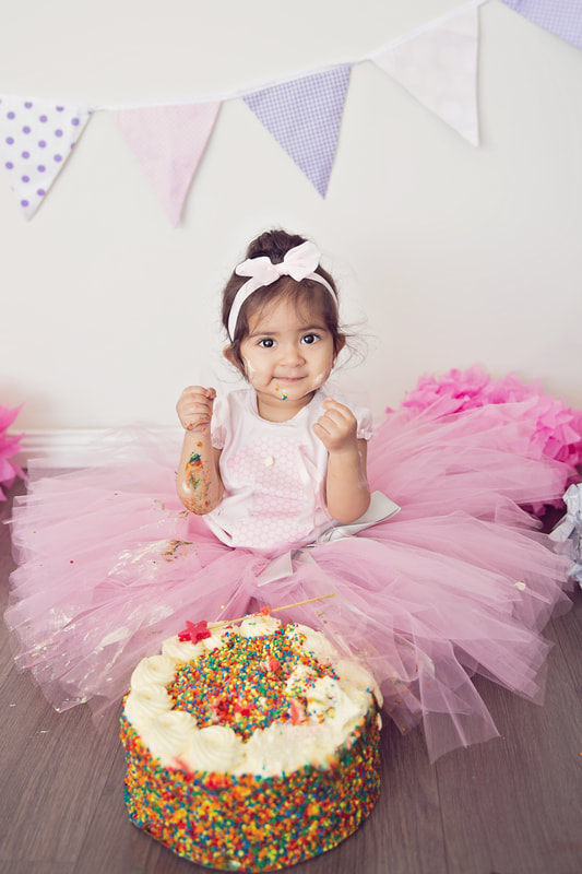Tiny Feet Photography little girl in pink smashing birthday cake