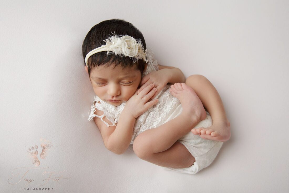Tiny Feet Photography image of a sweet baby girl in Lacey white outfit in Huck Finn Posed on white fabric