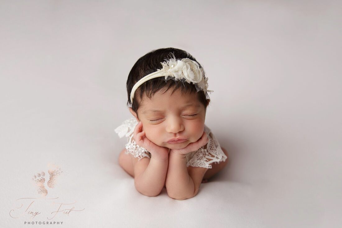 Tiny Feet Photography image of a sweet baby girl in Lacey white outfit in froggy pose on white fabric