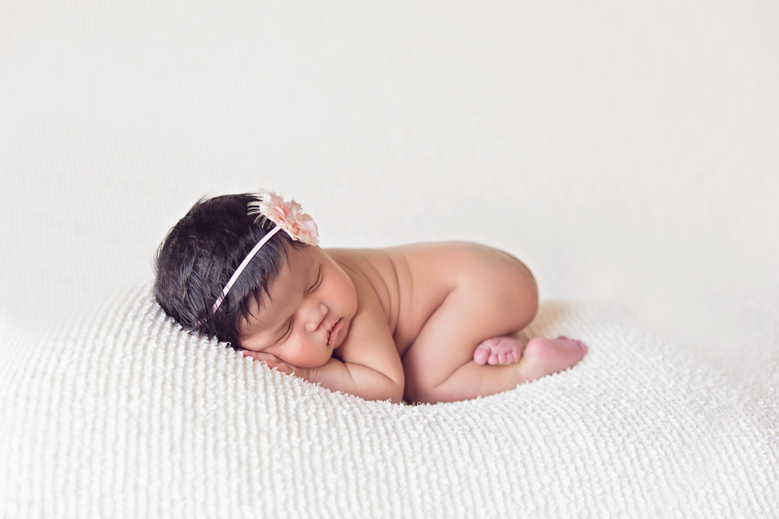 Newborn baby girl bum up posing on cream blanket on beanbag